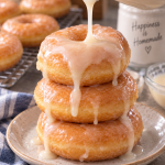Vanilla glaze being drizzled over a stack of homemade yeast donuts